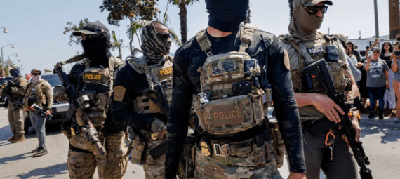 Masked ICE agents in military-style gear patrol a Southern California street during a June 2025 immigration raid (Bell, CA). Such scenes have become disturbingly common as federal raids sweep through communities.